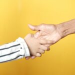 a person holding a child's hand with a yellow background